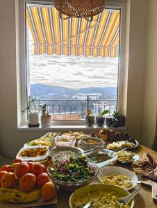 a table with many plates of food and a window at GLEDKA Apartament in Veliko Tŭrnovo