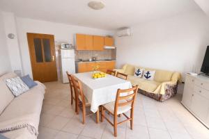 a kitchen and living room with a table and chairs at Apartmani Čop Rab in Banjol