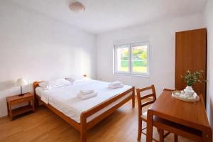 a bedroom with a bed and a table and a window at Apartmani Čop Rab in Banjol