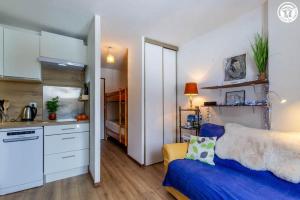 a living room with a blue couch and a kitchen at Dans les mélèzes in Saint-Pancrace