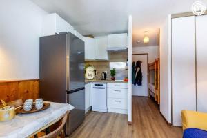 a kitchen with white cabinets and a large refrigerator at Dans les mélèzes in Saint-Pancrace