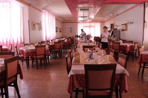 a restaurant with tables and chairs and a woman standing in a room at Hotel Kennedy in Caorle +15 photos