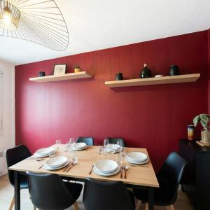 a dining room with a wooden table and red wall at L'Atelier Eiffel Moderne & confortable in Saint-Brieuc