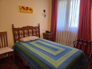 a bedroom with a bed with a blue and green striped blanket at Hotel Rural Las Farolas in San Rafael