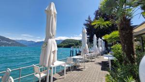 a row of white chairs and umbrellas on the water at Swiss Lakeside Apartments in Spiez