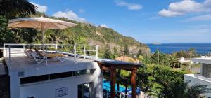 a balcony with an umbrella and chairs and the ocean at Quinta do Mar in Água de Pau