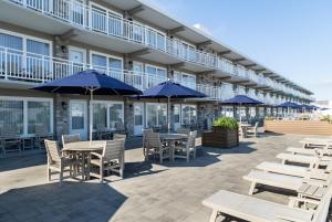 a patio with tables and chairs and blue umbrellas at Concord Suites in Avalon