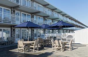 a patio with tables and chairs and blue umbrellas at Concord Suites in Avalon +3 photos