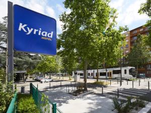 un panneau pour kyrid à côté d'une rue avec un train dans l'établissement Kyriad Grenoble Centre, à Grenoble