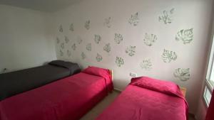 two beds in a room with pink sheets at Apart Hostel habitación con baño privado in Marcos Juárez
