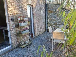 a patio with a table and chairs and a brick wall at La Maison des Senteurs in Francorchamps