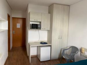 a small kitchen with a desk and a microwave at Flats da Júnia, ótimo benefício, fácil check-in, wifi , tv, ar, garagem, localizacao in Lagoa Santa