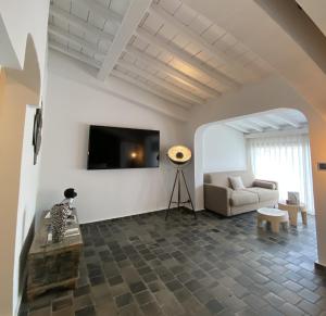 a living room with a couch and a tv on a wall at Hôtel Le Roi Théodore & Spa in Porto-Vecchio