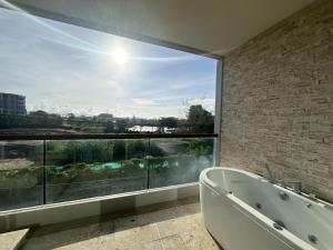 a bathroom with a large window and a bath tub at Boat Avenue Apartment in Bang Tao Beach