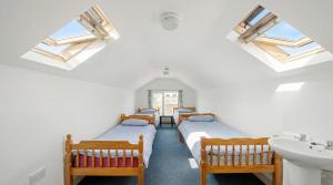 a row of beds in a room with skylights at Breakwater Hostel in Newquay