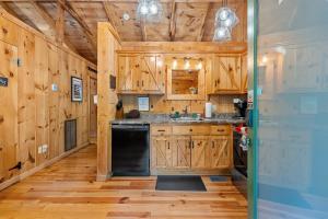 a kitchen with wooden cabinets and a black dishwasher at Tennessee Whisper Cabin in Sevierville