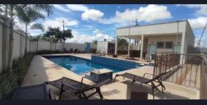 a swimming pool with two benches next to a house at Gran Torino in Aparecida de Goiânia