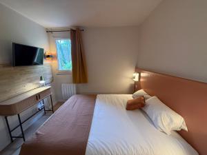 a bedroom with a bed and a desk and a television at Logis Hôtel La Cascade - Lyon Nord in Saint-Genis-les-Ollières
