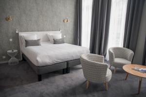 a bedroom with a bed and two chairs and a table at Hôtel de Tourny - Boutique Hôtel Bordeaux Centre in Bordeaux