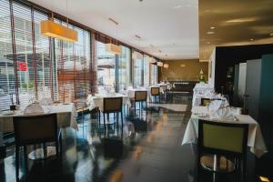 a restaurant with white tables and chairs and large windows at Quinta Mirabela - Design Hotel in Funchal