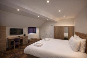 a bedroom with a bed and a desk and a television at The Miles Arms Hotel in Avonmouth