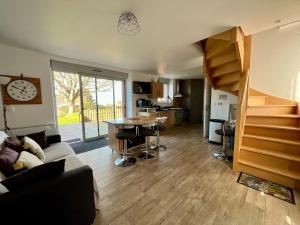 a living room with a spiral staircase and a living room at L'Erable - Maison vue mer in Donville-les-Bains