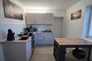a small kitchen with white cabinets and a table at Ferienwohnung NR3 in Großräschen