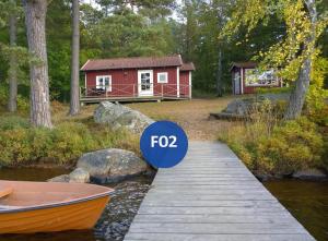 a small red cabin with a boat on a dock at Långasjönäs Camping & Stugby in Karlshamn