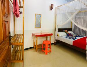 a bedroom with a bed with a red stool and a table at Dream Haven Mirissa in Mirissa