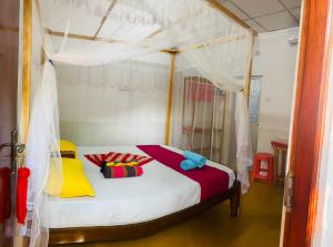 a bedroom with a canopy bed with colorful pillows at Dream Haven Mirissa in Mirissa