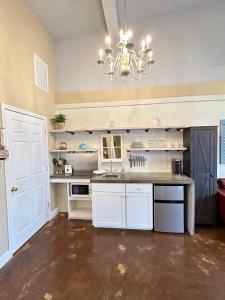 a large kitchen with a chandelier and white cabinets at Haven at Hazel~Downtown Bungalow in Demorest