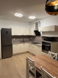 a kitchen with a wooden table and a refrigerator at Lima Apartment in Bernolákovo