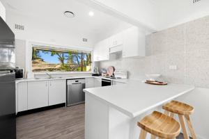 a white kitchen with a counter and two stools at Garrys After Dunes Delight in Norah
