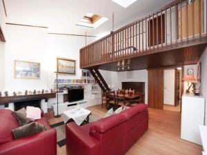 a living room with a red couch and a staircase at Parco Hermitage - Villa Azalea in Porto Valtravaglia