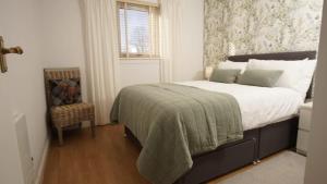 a bedroom with a bed and a chair and a window at Cosy flat in Inverness