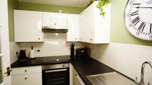 a kitchen with white cabinets and a large clock on the wall at Cosy flat in Inverness