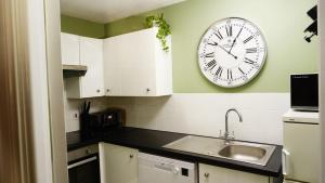 a kitchen with a clock on the wall and a sink at Cosy flat in Inverness +5 photos