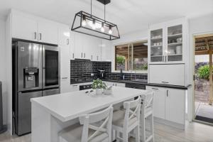 a white kitchen with a white table and appliances at Wangi Waters and Views in Wangi Wangi