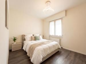 a white bedroom with a large bed and a window at Design Penthouse with Balcony - Iseo in Iseo