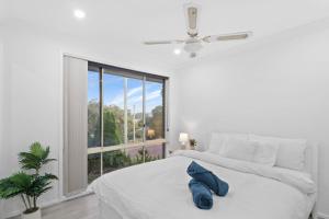 a white bedroom with a bed and a window at Wangi Waters and Views in Wangi Wangi