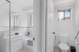 a white bathroom with a toilet and a sink at Wangi Waters and Views in Wangi Wangi