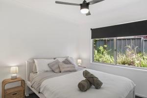 a white bedroom with a bed and a window at Play and Pool Bonnells Bay in Bonnells Bay +14 photos