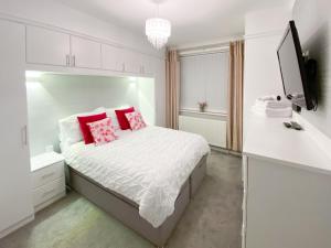 a white bedroom with a bed with pink pillows at Newcastle Lodge in Thornton