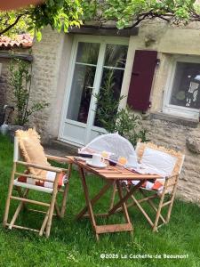 a picnic table and two chairs in front of a house at La Cachette de Beaumont in Marsais +41 photos