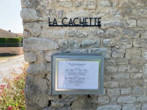 a sign on the side of a stone wall at La Cachette de Beaumont in Marsais