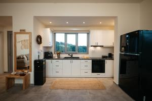 a kitchen with white cabinets and a black refrigerator at Irini's Beach House in Ambrami