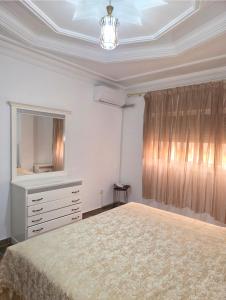 a bedroom with a bed and a dresser and a mirror at إقامة الكرنيش in Nador