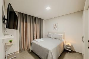a bedroom with a bed and a flat screen tv at Alto padrão, 2 suítes e lazer privativo in Joinville