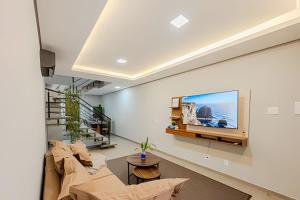 a living room with a couch and a tv on a wall at Alto padrão, 2 suítes e lazer privativo in Joinville