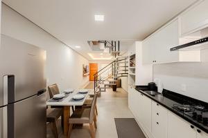 a kitchen with white cabinets and a table and chairs at Alto padrão, 2 suítes e lazer privativo in Joinville
